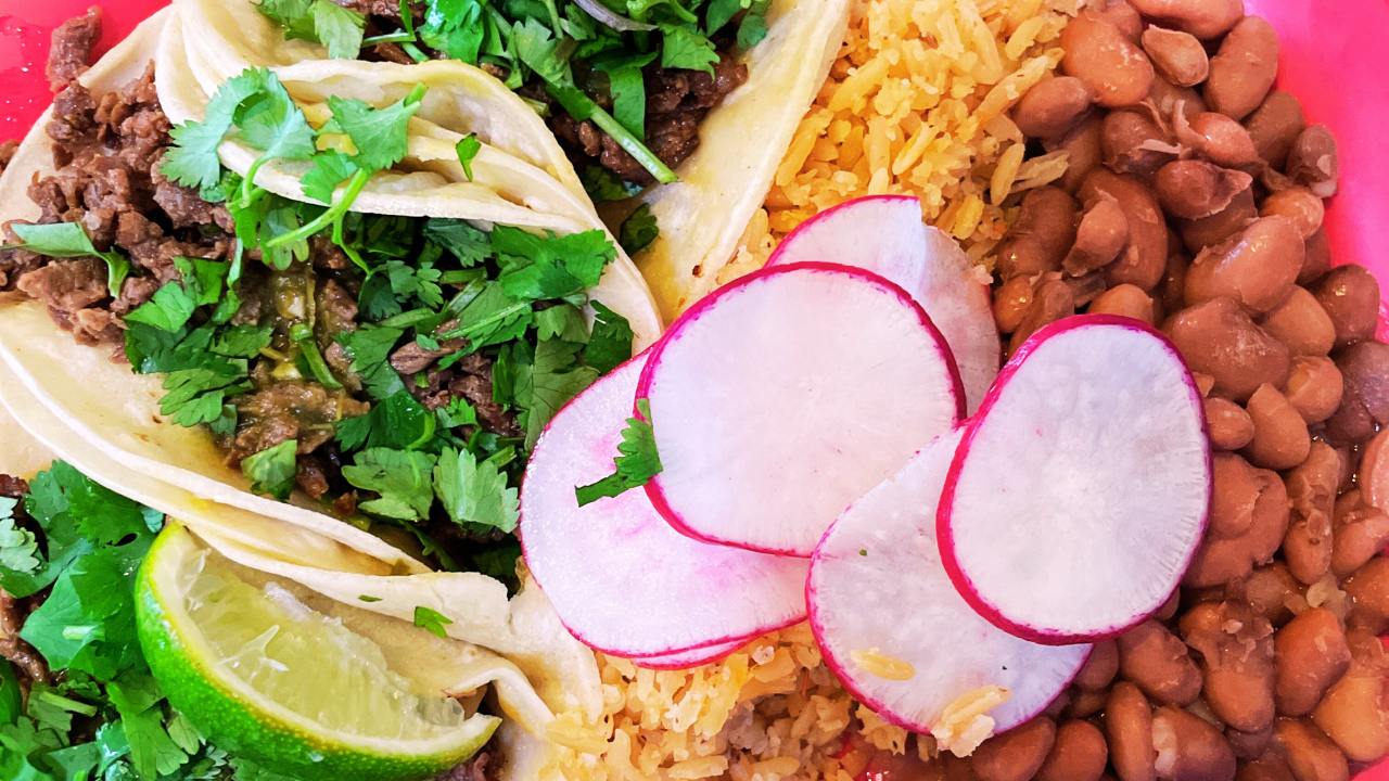 Carne asada tacos with rice, beans, cilantro, and radishes.