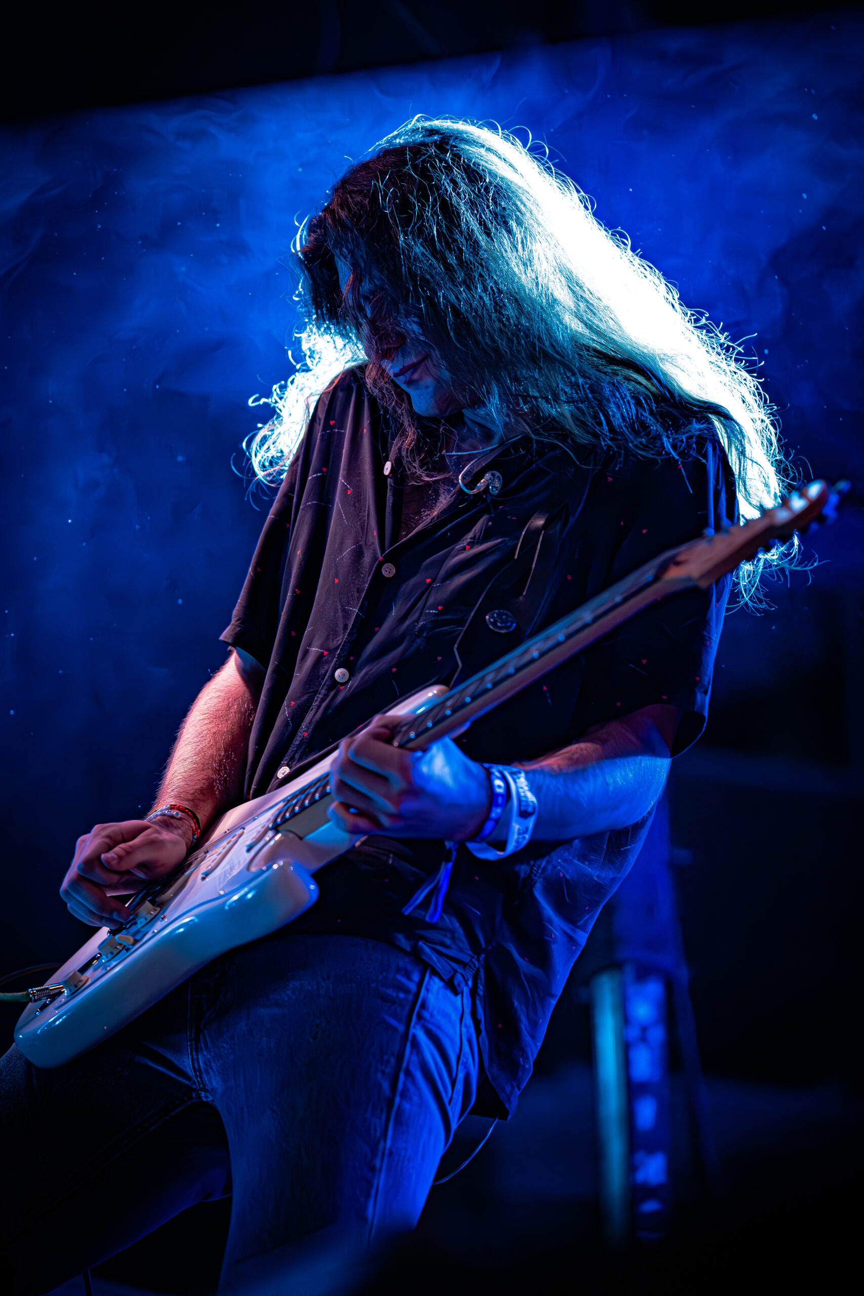 Guitarist immersed in a solo under vibrant blue lights.