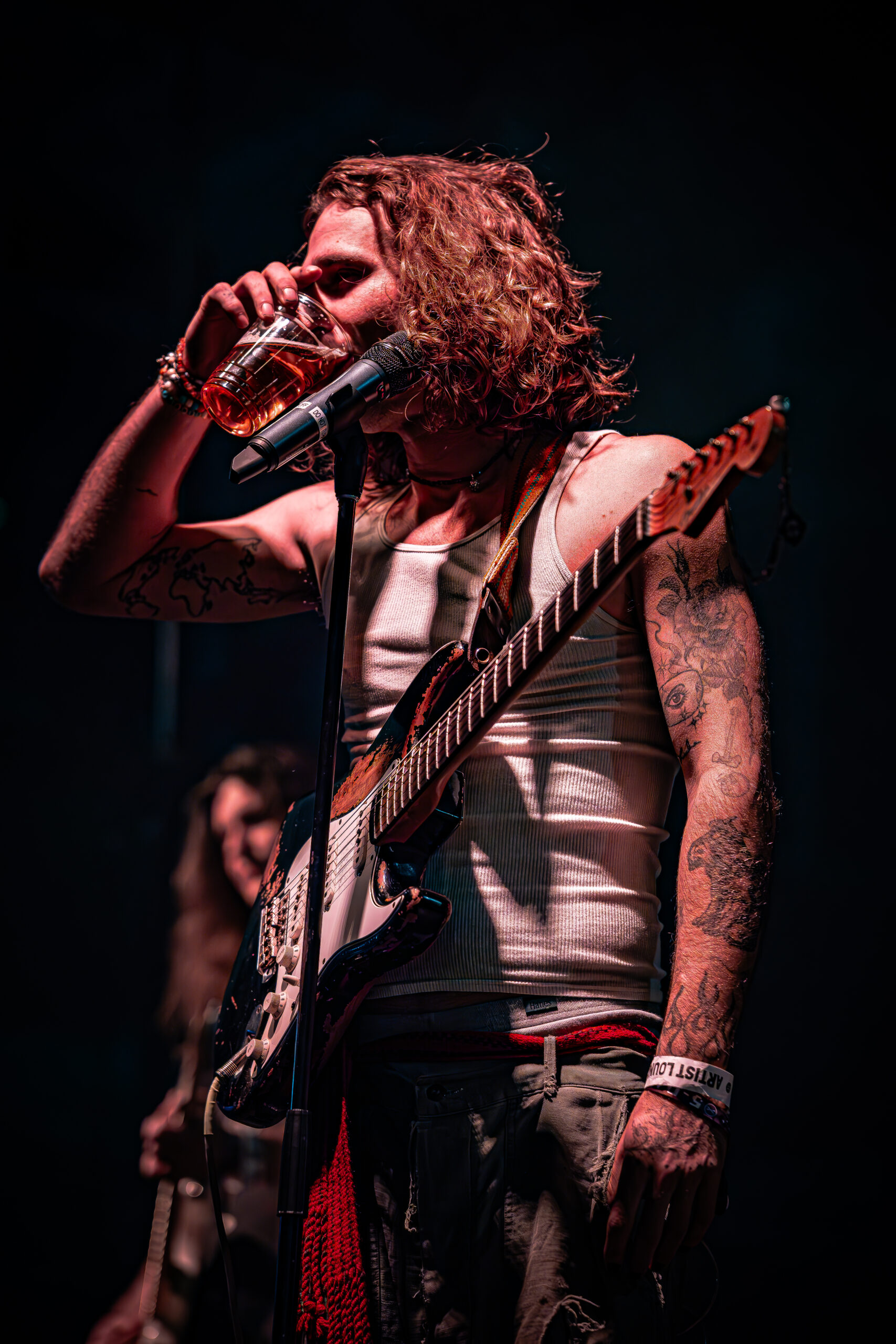 Musician on stage taking a break with a drink.