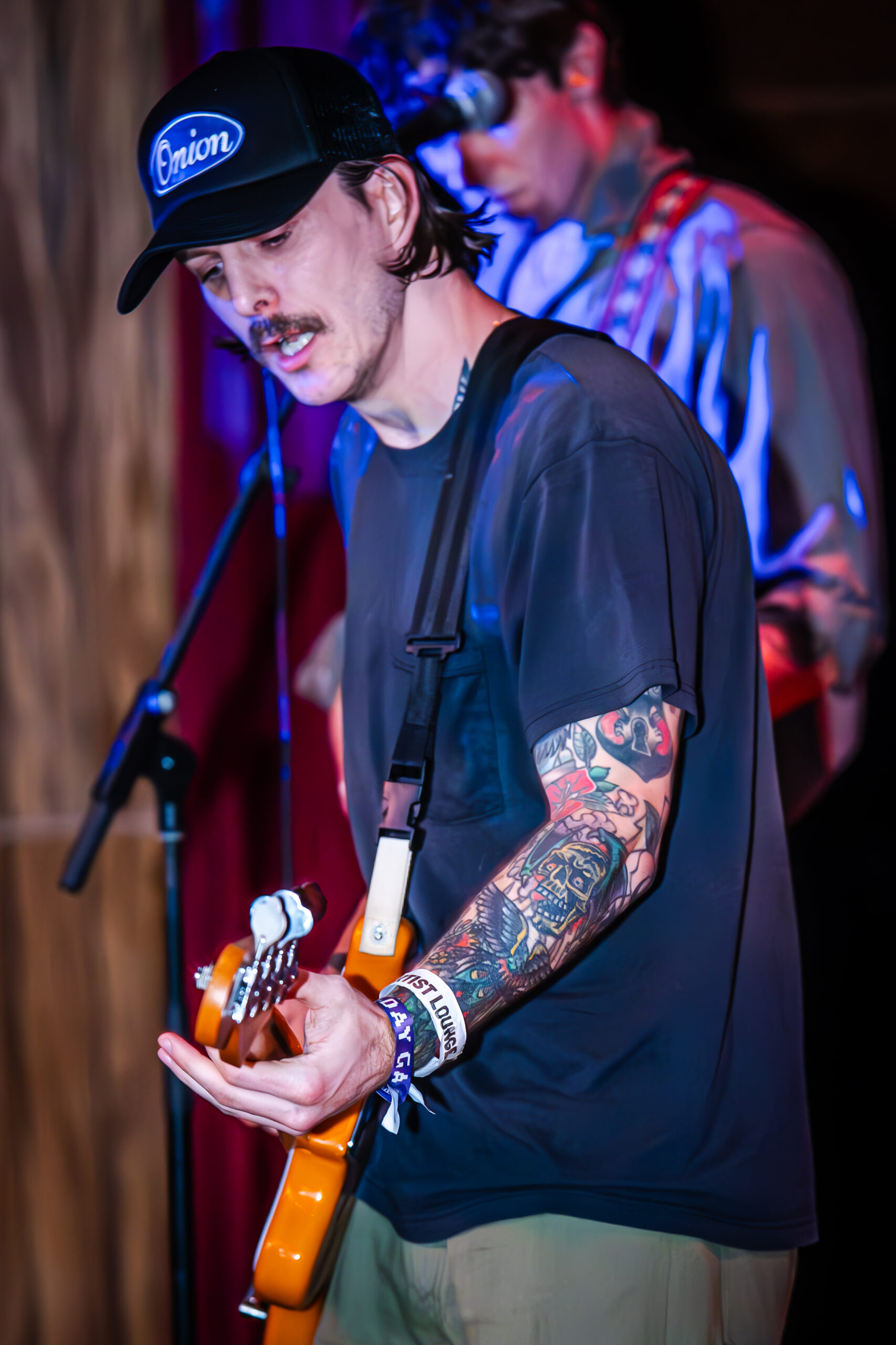 Musician in a baseball cap playing guitar.