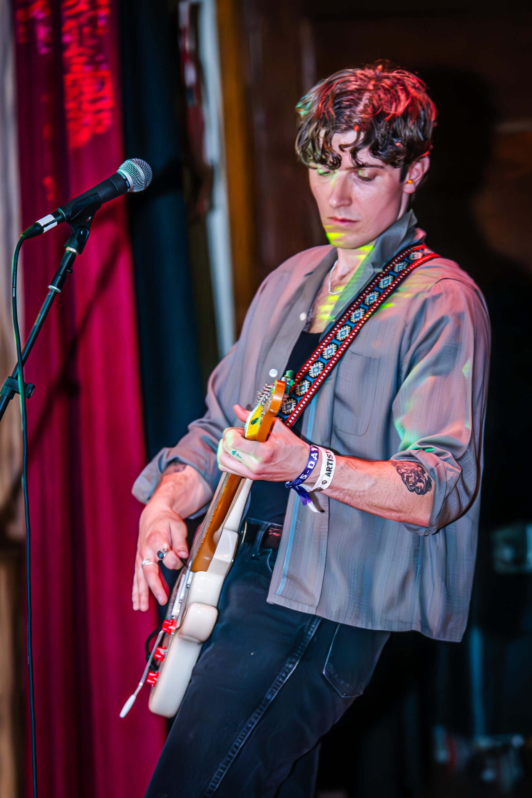 Musician in a grey blazer playing guitar.