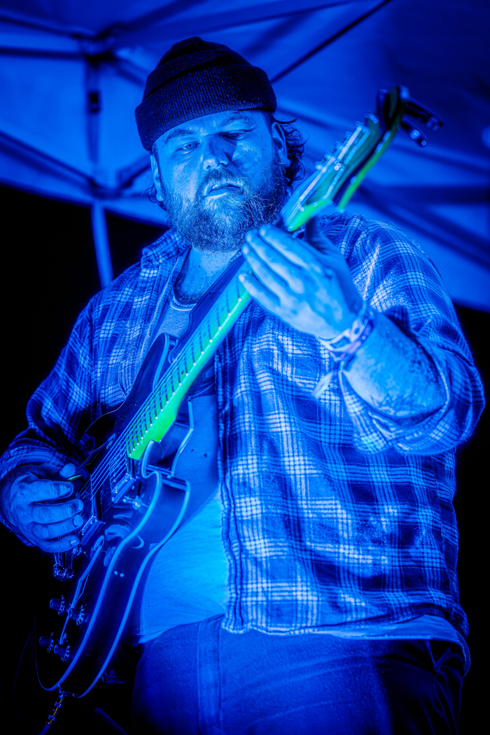 Jack Stablein of Brother Elsey focused on playing his guitar, illuminated by stage lights.