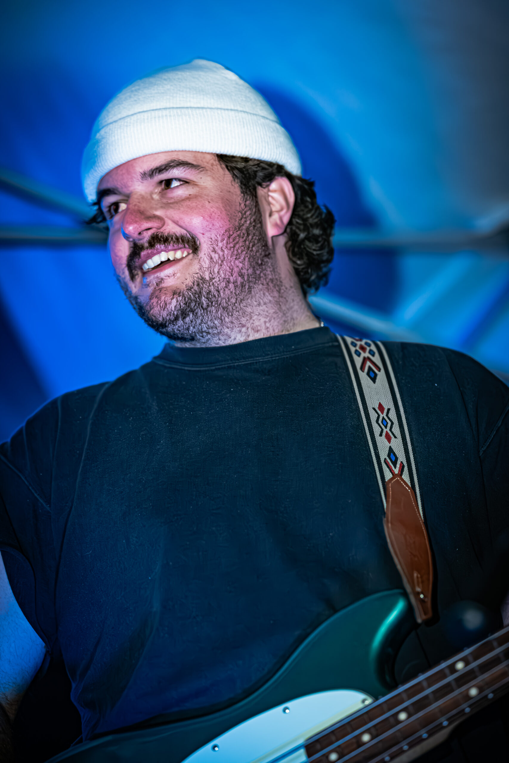 Beau Stablein of Brother Elsey smiles while playing bass guitar on stage.