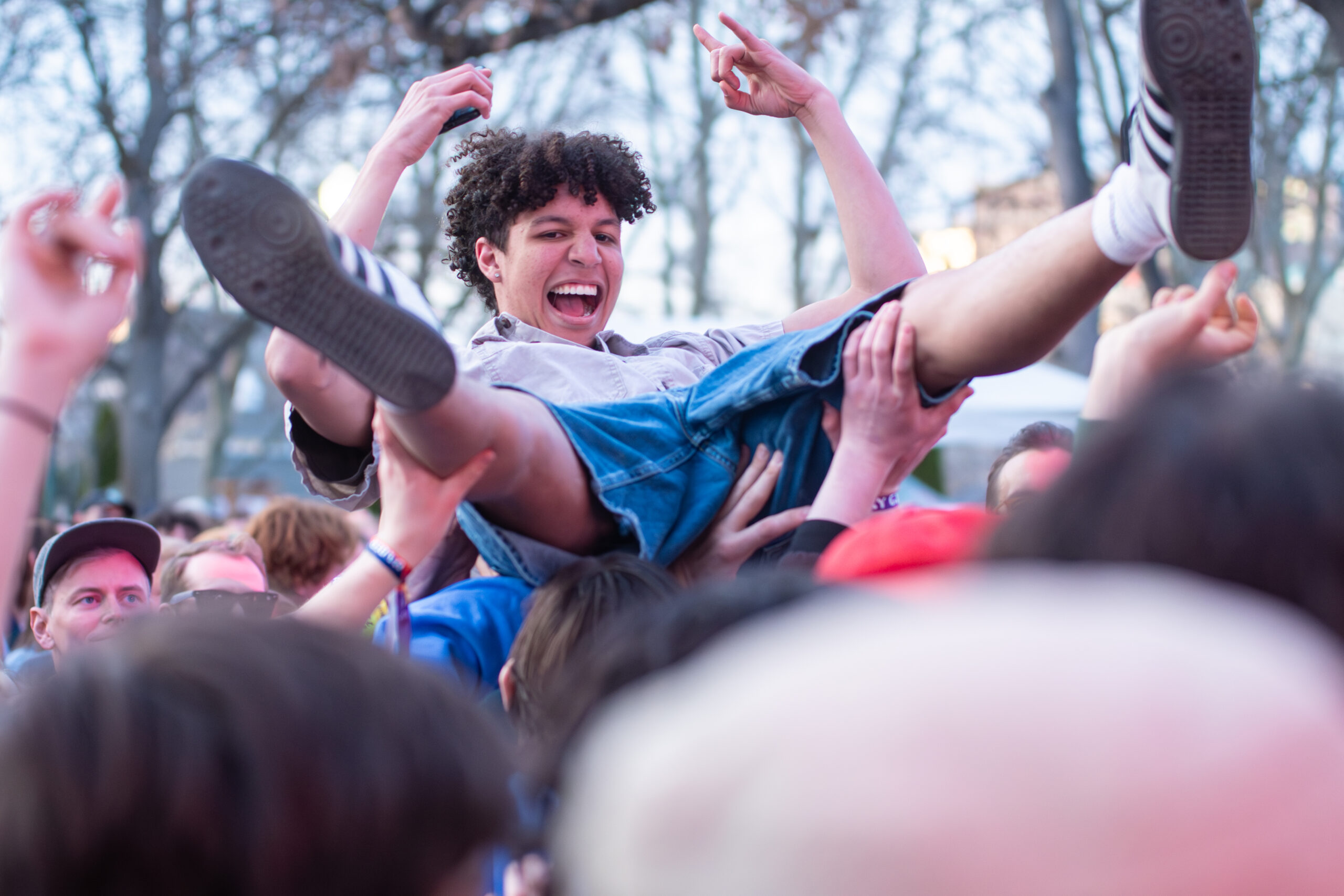 Close-up of a joyous fan being crowd-surfed at a concert.