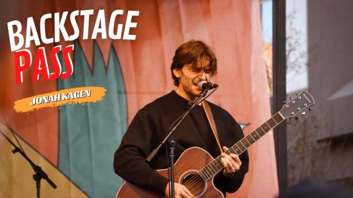 Jonah Kagen performing live at Treefort Music Festival 2024, singing into a microphone with a guitar in hand, spotlight illuminating his expressive face.