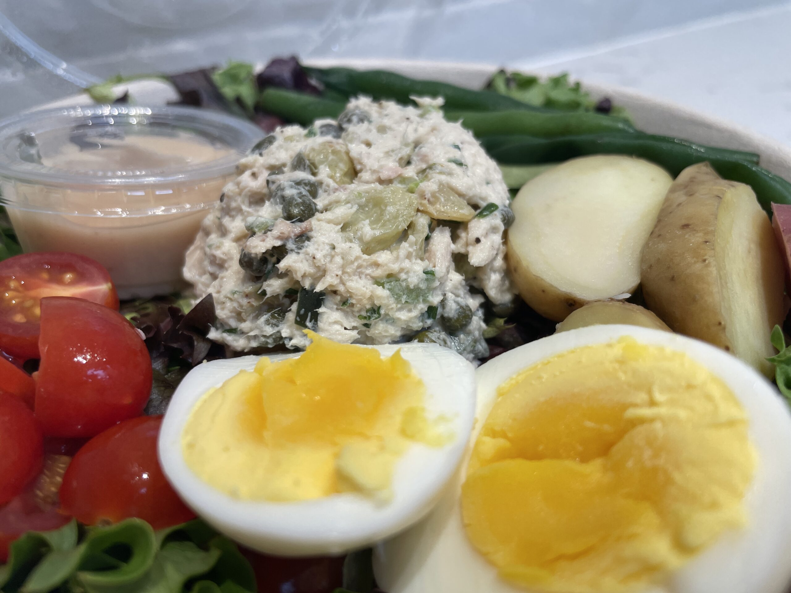 Fresh Tuna Nicoise salad with mixed greens, olives, roasted potatoes, tomatoes, and green beans, dressed in garlic vinaigrette at Certified Bakery.