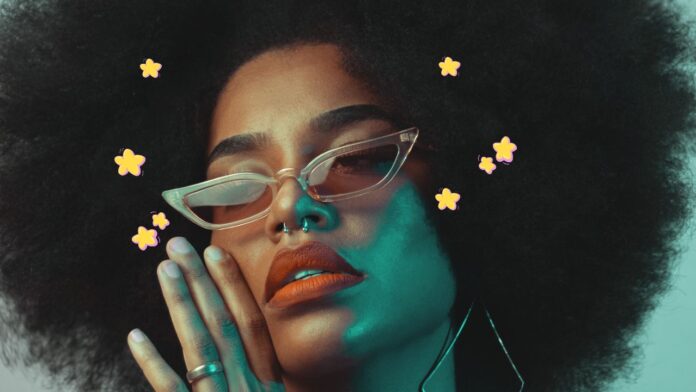 A close-up portrait of a person with dark skin, an afro hairstyle, and wearing cat-eye sunglasses. The person has a serene expression with their hands gently touching their face. Yellow star-shaped accents are scattered around the image, adding a whimsical touch.