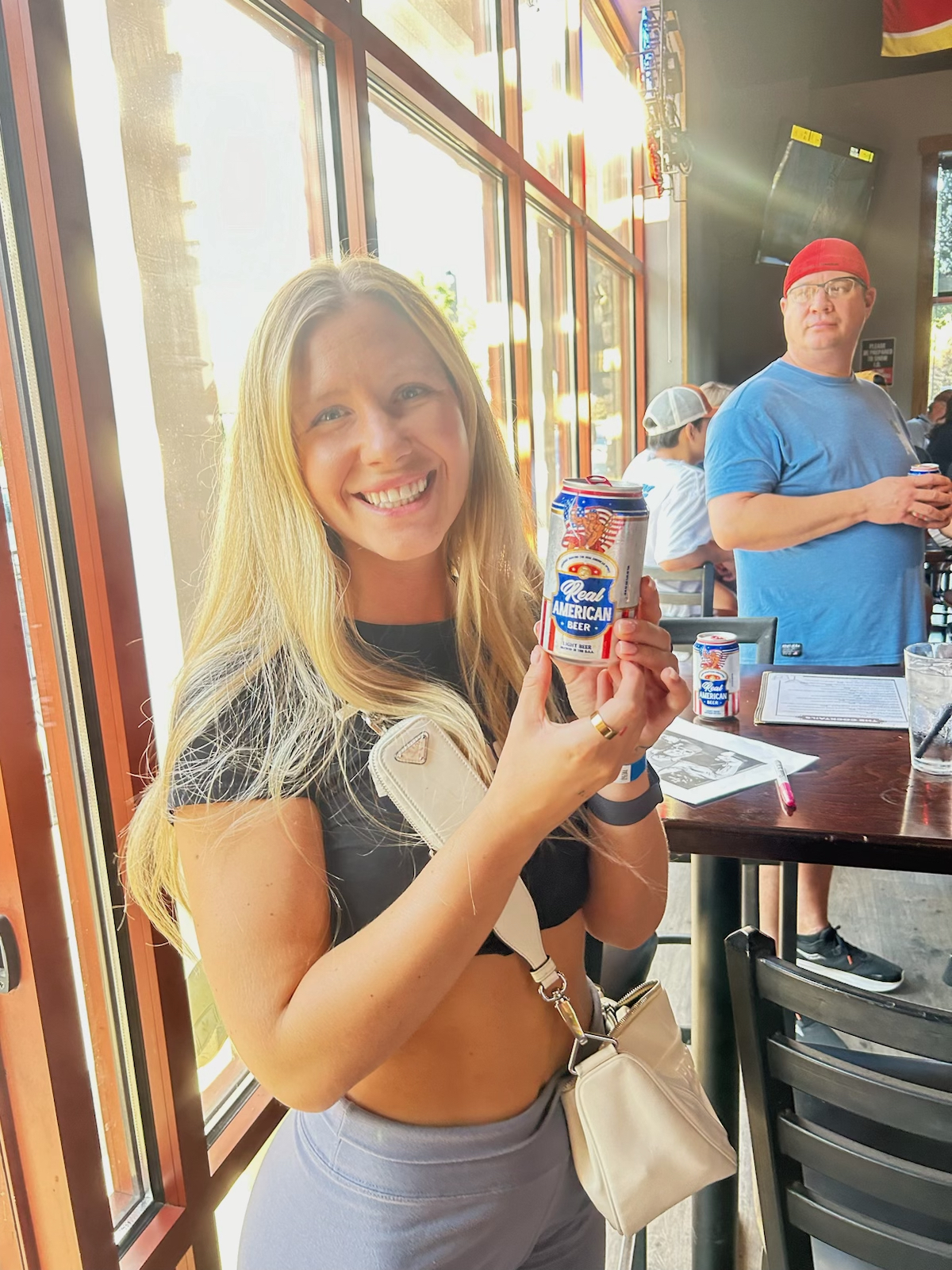 A young, pretty, blonde girl smiles while holding a Real American Beer in Giggy D's in Meridian Idaho during a Hulk Hogan promotion.