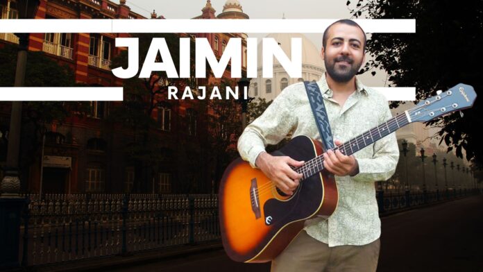 Jaimin Rajani holding a guitar, standing in front of an iconic Kolkata city backdrop, featuring historical architecture and a serene street view.