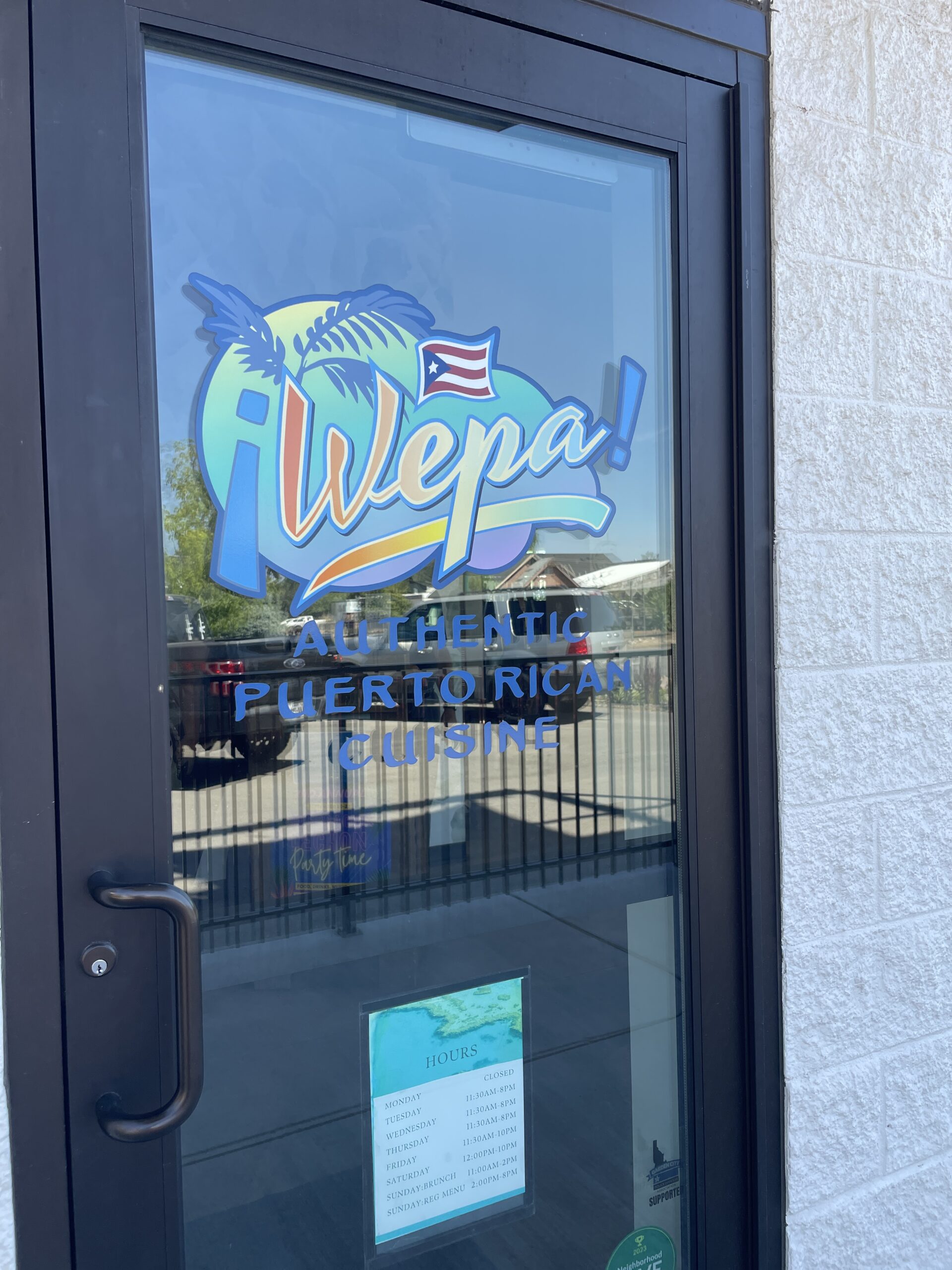 Wepa Café entrance door with colorful logo and business hours.