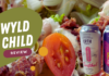 Wyld Child Review - Close-up of the Wedge salad with cherry tomatoes, crumbled bacon, creamy dressing, and two cans of Erth Beverage Co drinks, featuring Raspberry Ginger Switchel and Squirrel Punch flavors.