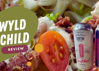 Wyld Child Review - Close-up of the Wedge salad with cherry tomatoes, crumbled bacon, creamy dressing, and two cans of Erth Beverage Co drinks, featuring Raspberry Ginger Switchel and Squirrel Punch flavors.