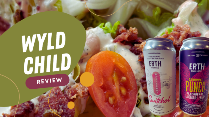 Wyld Child Review - Close-up of the Wedge salad with cherry tomatoes, crumbled bacon, creamy dressing, and two cans of Erth Beverage Co drinks, featuring Raspberry Ginger Switchel and Squirrel Punch flavors.