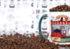 A colorful Push and Pour coffee mug filled with coffee beans, surrounded by scattered coffee beans.