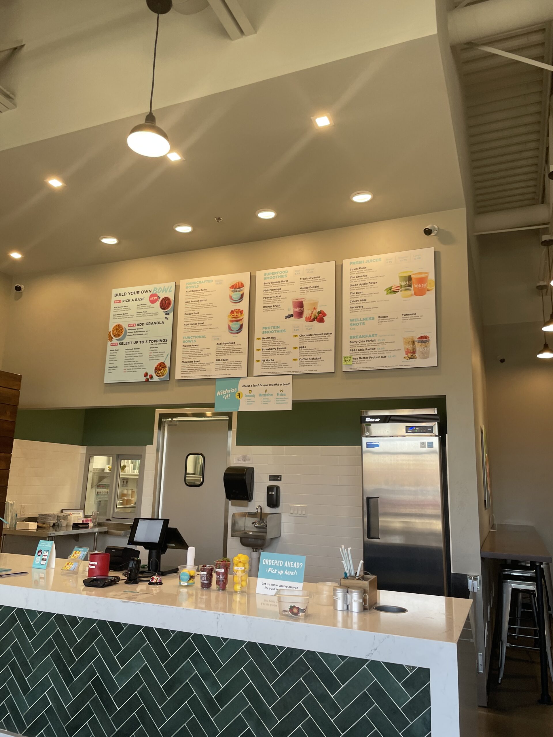 Inside Nekter Juice Bar in Meridian, Idaho, featuring a clean counter, digital ordering system, and a menu displaying smoothies, acai bowls, and wellness shots.