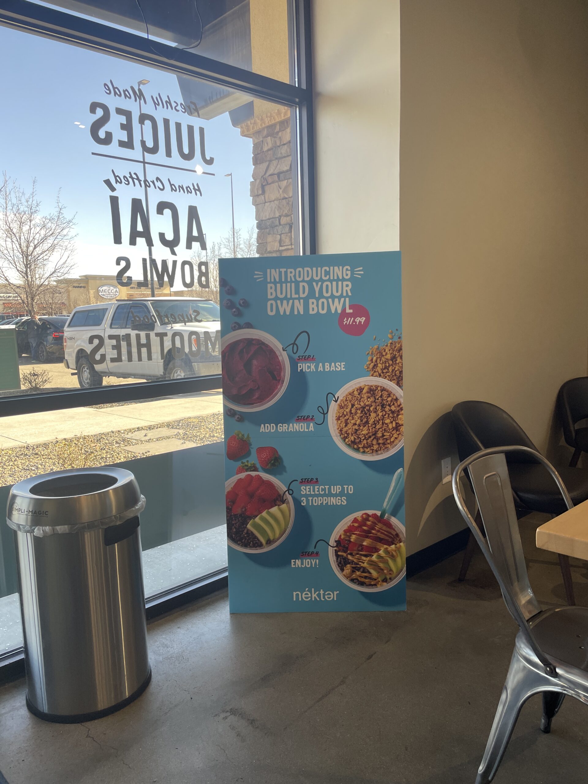 A Nekter Juice Bar promotional sign inside the store, advertising the 'Build Your Own Bowl' option with acai, granola, and toppings.