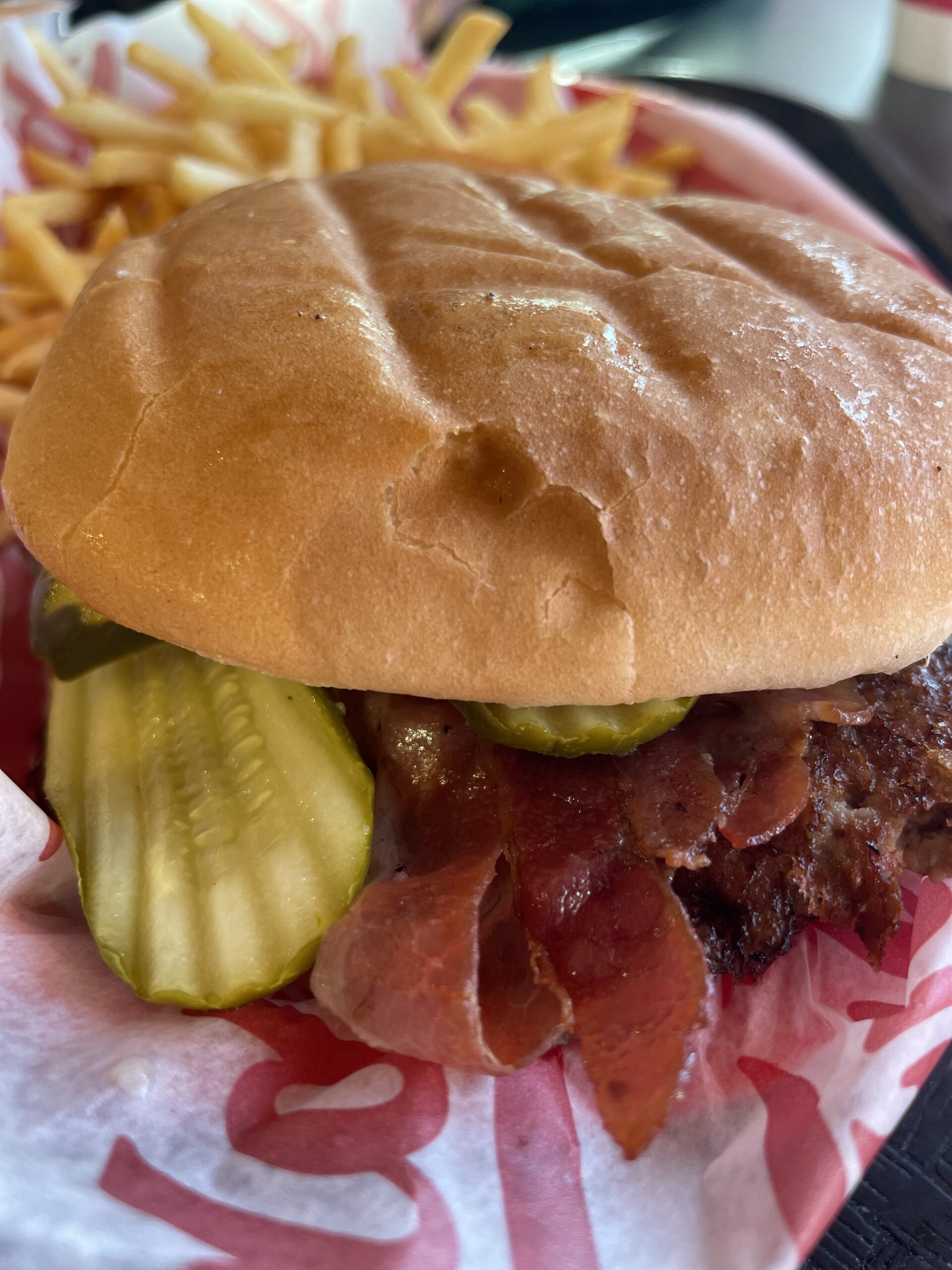 A Freddy’s steakburger with crispy bacon, pickles, and a toasted bun.