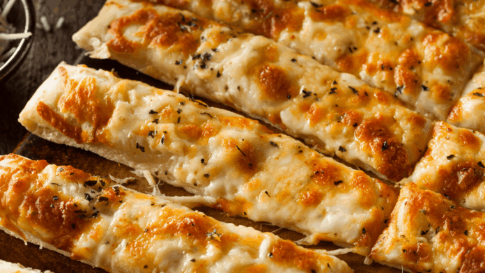Cheesy garlic breadsticks with melted mozzarella and herbs served on a wooden board