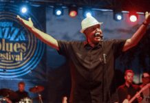Johnny Rawls on Soul-Blues Legacy, Mississippi Roots & His New Album Make Them Dance Johnny Rawls performing live on stage at a jazz and blues festival, arms raised wide while singing into the microphone.