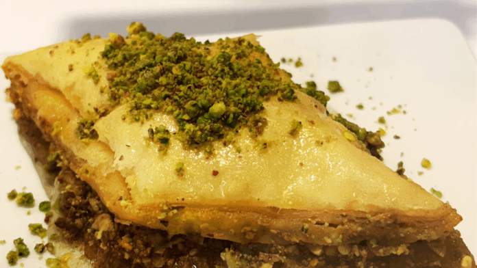 Close-up of Pistachio Baklava at Sunshine Spice Bakery & Café in Boise, Idaho, featuring layers of flaky filo pastry, crushed pistachios, and honey glaze.