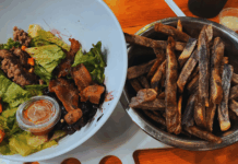 Boise Fry Company Review: Fries First, Burgers on the Side in Boise’s Treasure Valley Fresh green salad topped with ground bison, crispy bacon, and blueberry compote, served alongside a metal bowl of thick-cut purple heirloom fries at Boise Fry Company.