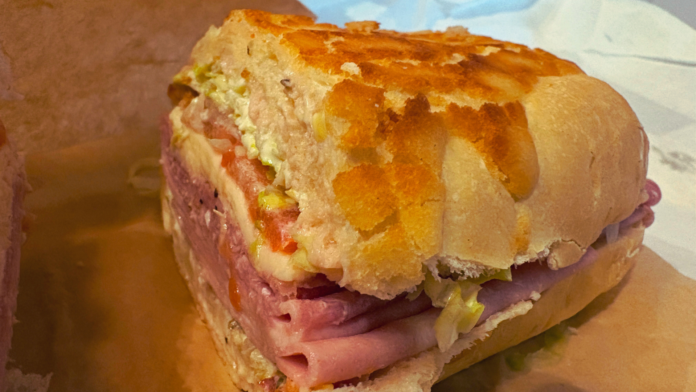 Close-up of Fratelli Deli’s Godfather sandwich on house-baked Dutch Crunch bread, layered with Italian meats, provolone, lettuce, tomato, and spicy giardiniera.