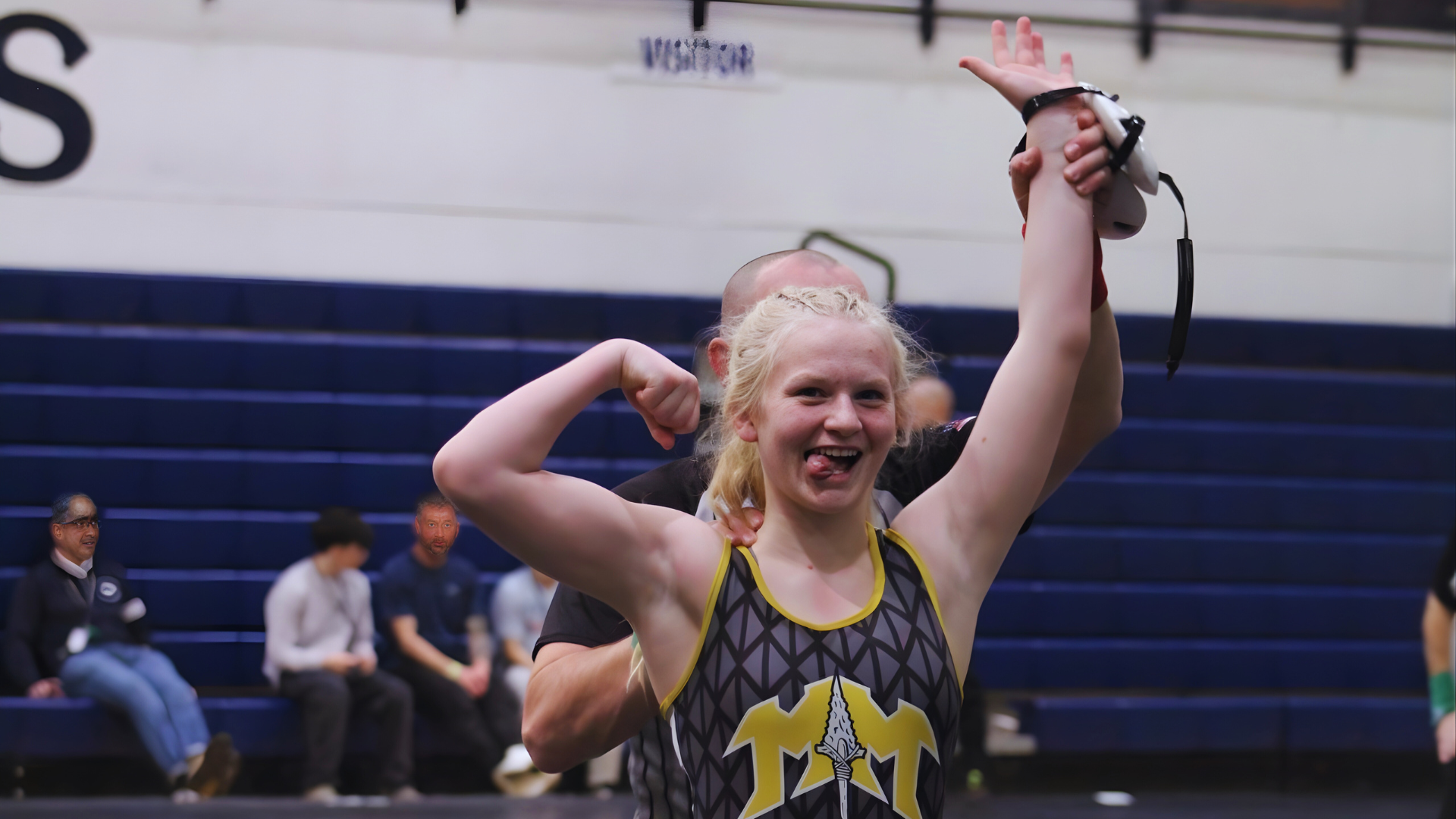 Middle school girl wrestler from Meridian flexes triumphantly after winning a match at the West Ada District Championship.