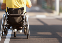 The Power of Being Seen: Why Purpose-Driven Care Is Reshaping Community Impact Person using a wheelchair crossing a city street, symbolizing dignity, independence, and human-centered disability support discussed in The Power of Being Seen podcast.