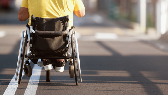 You Are Seen Person using a wheelchair crossing a city street, symbolizing dignity, independence, and human-centered disability support discussed in The Power of Being Seen podcast.