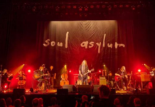 Dave Pirner on Soul Asylum’s Next Chapter & MPLS Unplugged Soul Asylum performs live onstage under red concert lighting, with guitars, strings and the band’s handwritten logo projected behind them.